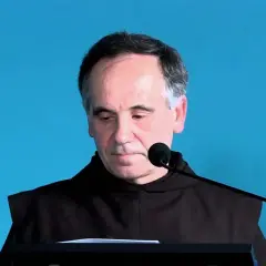 Mężczyzna w habicie, jeden z mistycy nadreńscy, pochyla się nad pulpitem.
