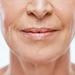 Primo piano del volto di una donna anziana, con particolare attenzione alle labbra e alle rughe labiali che raccontano storie di vita.