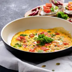 Omlet z pomidorami i ziołami na patelni. Idealny pomysł, jak ograniczyć węglowodany w diecie.