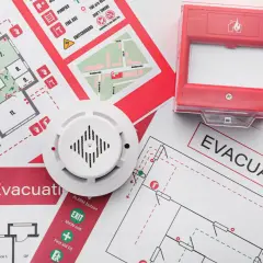 Piani di evacuazione e un rilevatore di fumo, elementi essenziali per la valutazione del rischio incendio.