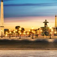 Place de la Concorde i Paris med obelisk, fontän och Eiffeltornet i skymningen. Gatlyktor lyser upp torget.