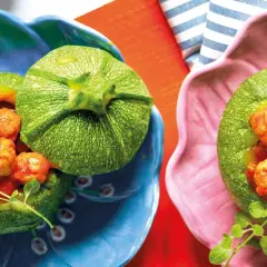 Zucchine tonde ripiene di polpettine in salsa, servite in ciotole colorate. Un piatto invitante e gustoso.