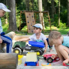 Dzieci w piaskownicy bawią się zabawkami, co wspiera ich rozwój fizyczny w wieku przedszkolnym.