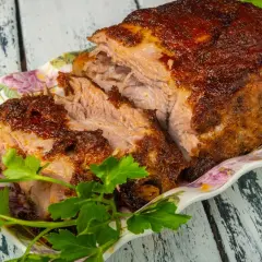 Soczysta karkówka po zbójnicku w plastrach, pieczona do perfekcji, podana z ziołami na ozdobnej paterze.