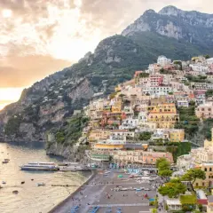 A stunning view of Positano, perfect for your Amalfi Coast 2-day itinerary. Colorful houses cascade down a steep cliff to a beach dotted with boats.