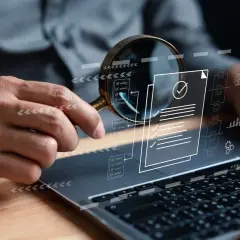 Analiza dokumentów i danych na laptopie, symbolizująca finanse i controlling. Powiększenie pomaga w dokładnym przeglądzie.