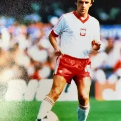 Piłkarz w biało-czerwonym stroju, jeden z legendarnych polscy piłkarze lat 90., drybluje na boisku.