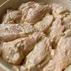 Råa kycklingbitar i en krämig marinad. Denna yoghurtmarinerade kyckling ser ut att bli otroligt saftig och smakrik.