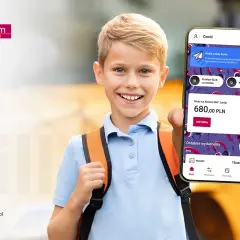 Uśmiechnięty chłopiec z plecakiem pokazuje telefon z aplikacją bankową. Na ekranie widnieje informacja o koncie dla dziecka Millennium 360° Junior z saldem 680 zł.