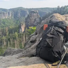 Rucksack und Wanderstöcke auf Felsen mit Bergpanorama. Alles pvc frei für umweltbewusstes Trekking.
