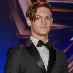 Młody mężczyzna w garniturze i muszce, gotowy na występ w Mam Talent 2024.