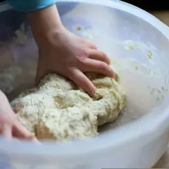 Manos de niño amasando masa para una deliciosa receta de masa de pizza casera en un bol.