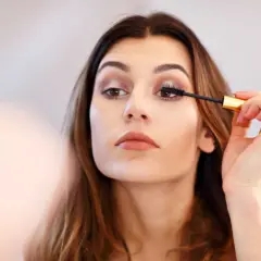 Une femme applique du mascara sur ses cils. Elle apprend comment mettre du mascara pour un regard intense.