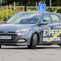 Szara Skoda z literą L na dachu, oznakowana jako "Szkoła Jazdy EXPERT". Pytanie o prawo jazdy od ilu lat jest tu na miejscu, bo to auto do nauki jazdy.