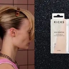 En person stylar ett elegant hårknut med en klämma. Bredvid syns en förpackning med Kicks mini-elastik för diskreta frisyrer.