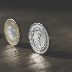 Dwie polskie monety, 1 złoty i 2 złote, na drewnianym blacie. Marzenie o pensji 6500 brutto.