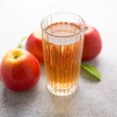 Glas mit Apfelsaft und Äpfeln. Über Apfelessig trinken Nachteile nachdenken.