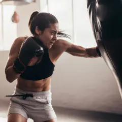 Focused female boxer practices double end bag drills, her punches a blur of motion.