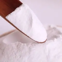 Biały proszek na drewnianej łyżce. To mogą być difosforany, składnik wielu produktów.