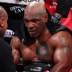 Mike Tyson, sweaty and focused, receives advice from his corner. His "Mike Tyson schedule" is etched in his determined expression.