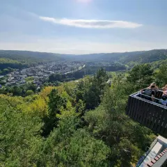 Widok z punktu widokowego w Rumi na zieloną dolinę i miasto. Kilka osób podziwia panoramę.