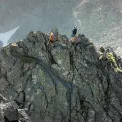 Dwóch alpinistów pokonuje skalisty grzbiet. Jeden z nich schodzi po linie, drugi obserwuje. To trudna droga Martina na Gerlach.