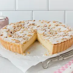 Eine köstliche Torta della Nonna, bestäubt mit Puderzucker und Pinienkernen, wartet darauf, angeschnitten zu werden.