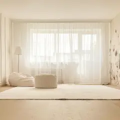 Jasne, przytulne wnętrze z dywanem, pufami i lampą. Eleganckie listwy okienne wewnętrzne podkreślają styl.