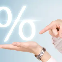 Dłoń wskazuje na duży znak procentu, symbolizujący pytanie: ile wynosi stopa procentowa?