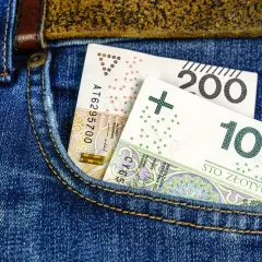 Polskie banknoty 100 i 200 zł w kieszeni dżinsów.