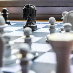 Czarny koń na szachownicy, gotowy do wykonania swojego charakterystycznego ruchu, jak porusza się koń w szachach.