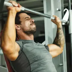 Mann hebt mit konzentriertem Gesichtsausdruck eine Langhantel im Fitnessstudio, ein intensiver 1 satz training.
