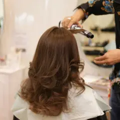 Styling włosów w domu: lokówka tworzy piękne fale na brązowych włosach.