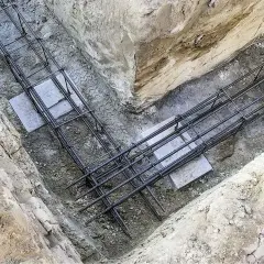 Gotowe zbrojenie fundamentu w wykopie. Stalowe pręty tworzą solidną konstrukcję, gotową na zalanie betonem.