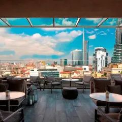 Terrazza panoramica con divani eleganti e vista sui grattacieli di Milano. Perfetto per godersi l'aperitivo nei locali chic milano.
