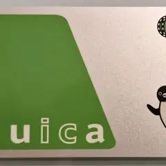 Eine Suica-Karte mit einem fröhlichen Pinguin-Motiv. Die Karte ist silberfarben mit einem großen grünen Feld und dem Schriftzug "Suica".