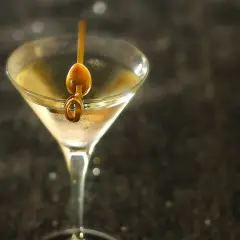Un verre à martini rempli d'un cocktail clair, garni d'une olive sur un cure-dent. Une image parfaite pour une vodka martini recette.