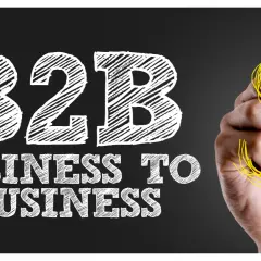 Mano disegna simbolo dollaro su lavagna con scritta "B2B Business to Business", il significato di B2B nel mondo degli affari.