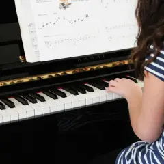 Une jeune fille joue du piano, ses doigts effleurant les touches pour créer une douce mélodie adagio musique.