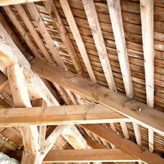 Vue rapprochée d'une pose de charpente en bois, montrant la complexité des poutres et des chevrons.