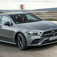 Szary Mercedes W177 pędzi po torze, kierowca w czerwonej koszuli pewnie trzyma kierownicę.
