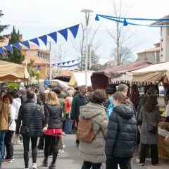 Gente paseando por el mercadillo de Noja, con puestos de artesanía y decoración bajo toldos.