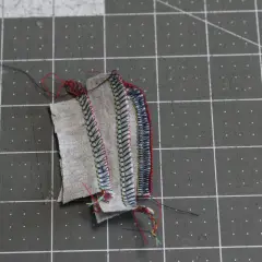 Serger troubleshooting: tangled threads and uneven stitches on fabric scraps.