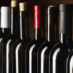 Bouteilles de vin alignées, certaines avec bouchons en liège, d'autres avec capsules. Un aperçu des trésors d'un domaine viticole Roussillon.