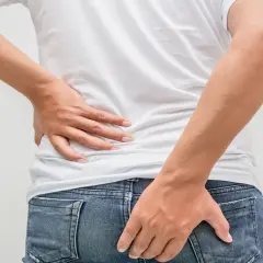 Mann hält sich den Rücken und das Gesäß. Möglicher tumor am after.