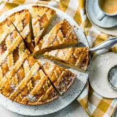 Ein köstliches Crostata-Rezept, aufgeschnitten und mit Puderzucker bestäubt, daneben eine Tasse Espresso.