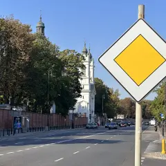 Znak "koniec drogi z pierwszeństwem" na tle kościoła i drzew. Ulica Burakowska w Warszawie.