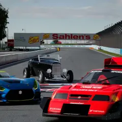 Trzy samochody wyścigowe na torze, w tym niebieski Suzuki, czerwony Suzuki i czarny hot rod. Grafika z gry Gran Turismo na PC.