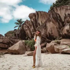 Kobieta w białej narzutce na plaży na Seszelach, wśród gigantycznych skał i palmy. Rajskie wyspy.