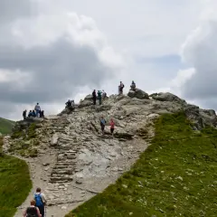 Grupa turystów na kamienistym szlaku górskim pod Kasprowym Wierchem.